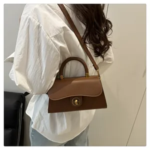 Brown retro shoulder bag with golden round swivel lock and curved handle detail
