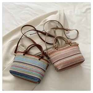 Detail showing two woven straw bucket bags with leather handles on a beige blazer