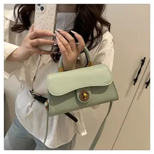 Close-up of the vintage gold twist lock and smooth leather texture on a green handbag