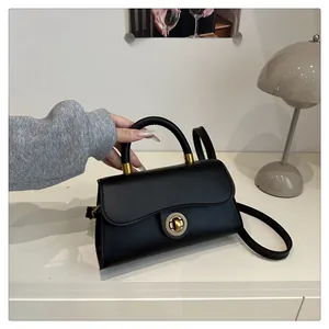 Detail of minimalist black faux leather handbag with golden metal lock on a table