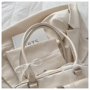 Détail d'un sac cabas en cuir blanc crème avec des anses cylindriques et un design spacieux