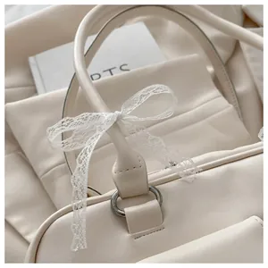 Détail d'un sac en cuir crème avec un élégant nœud en dentelle blanche sur l'anneau