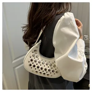 Detail of white half-moon underarm bag with silver metal studs on synthetic leather