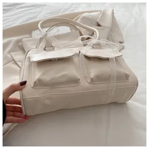 Détail du sac beige avec nœud en dentelle et poches avant à rabat élégantes
