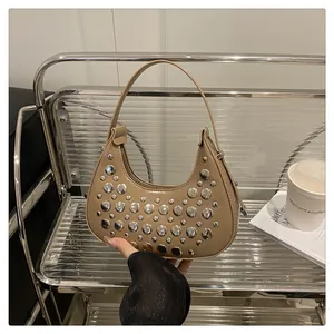 Macro detail of khaki PU leather half-moon bag with decorative silver rivets on a chair
