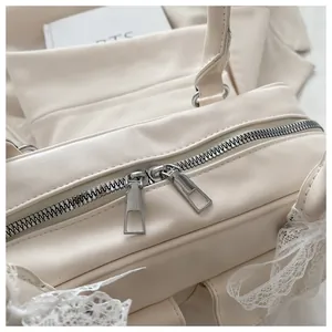 Vue détaillée du sac en cuir PU crème avec bordure en dentelle blanche et zip argenté