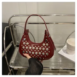 Detailed macro view of dark red hobo bag featuring polished silver metallic rivets