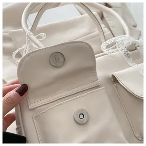 Détail du sac crème montrant le fermoir magnétique et le nœud décoratif en dentelle