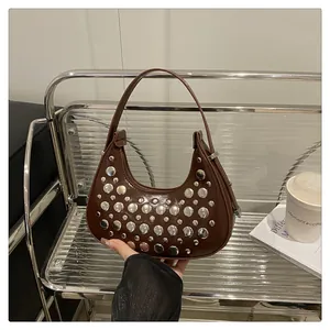 Detail of silver rivets on dark brown faux leather hobo bag with a polished surface