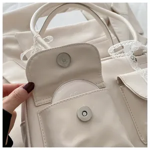 Détail de sac en cuir beige avec boucles magnétiques et bordure en dentelle blanche