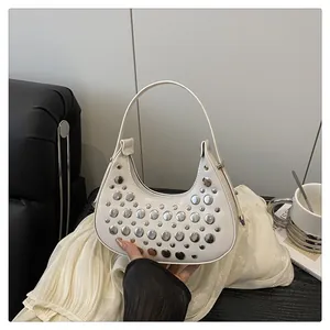 Detailed shot of white hobo bag with silver rivets held against a modern lifestyle setting