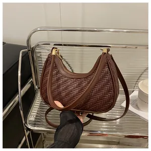 Dettaglio borsa a mezzaluna intrecciata marrone scuro con cerniera dorata e tracolla
