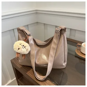 Détail du sac fourre-tout en similicuir marron avec coutures verticales et breloque en peluche