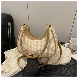 Dettaglio della borsa a mezzaluna intrecciata con texture beige e bordi in pelle marrone