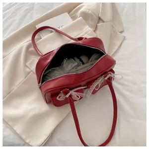 Détail du sac Boston rouge avec nœuds en dentelle blanche et grand espace de rangement