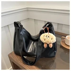 Détail du sac fourre-tout noir en cuir PU avec peluche biscuit sur une table basse