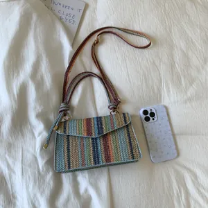 Colorful woven stripe crossbody bag with long strap on white textured background