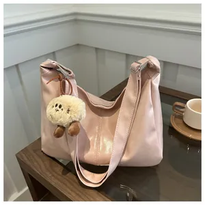 Détail du sac hobo en cuir PU rose avec un porte-clé en peluche sur une table
