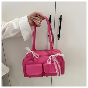 Détail de sac à main rose avec des nœuds en dentelle blanche et deux poches avant