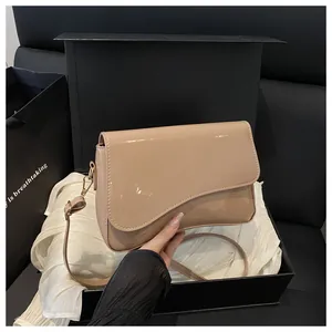 Detail of a milk tea colored glossy leather crossbody bag with asymmetric flap design