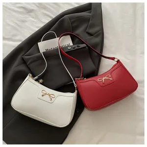 Detailed view of red and white bow shoulder bags on fabric background with gold hardware
