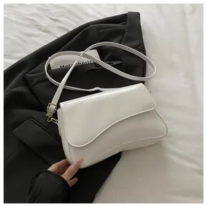 Detail of white patent leather shoulder bag with asymmetrical flap and gold hardware