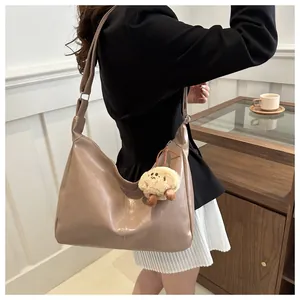 Gros plan du sac fourre-tout beige brillant avec un pendentif d'ours en peluche mignon