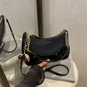 Glossy black patent leather hobo bag with gold chain and red cherry charm decoration