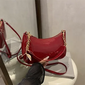 Red patent leather baguette bag with gold chain and cherry charm shown from multiple angles