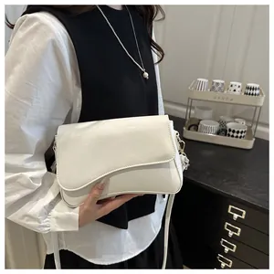 Detail of white glossy patent leather shoulder bag with unique curved bottom and gold hardware