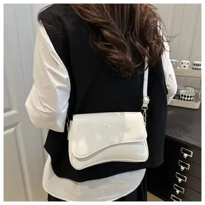 Detail of white glossy patent leather bag featuring unique wave-shaped flap and gold hardware