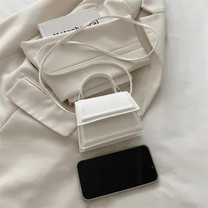 Mini white leather crossbody bag shown next to a smartphone to illustrate ultra-small size