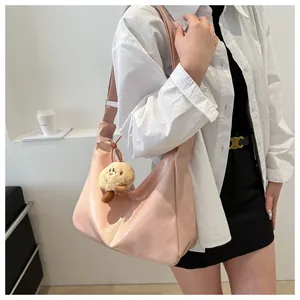 Vue latérale d'un sac hobo rose clair avec un pendentif en peluche sur le mannequin