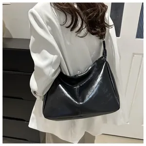 Sac cabas noir brillant en cuir verni porté par un mannequin pour un look urbain chic