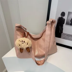 Sac hobo rose en cuir PU avec pendentif en peluche sur un support blanc épuré