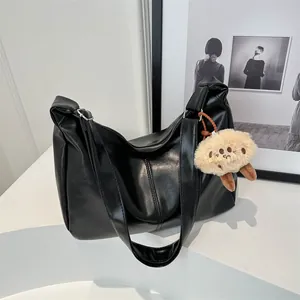 Sac fourre-tout minimaliste en similicuir noir avec pendentif monstre en peluche sur blanc