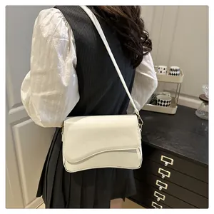 Primo piano di una borsa a spalla color crema minimalista con patta dal design asimmetrico