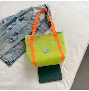 Detail of neon mesh tote bag featuring orange straps, mint trim, and breathable texture