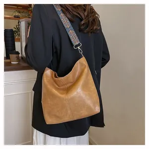 Brown PU leather tote bag with stylish wide patterned fabric strap in a cafe setting