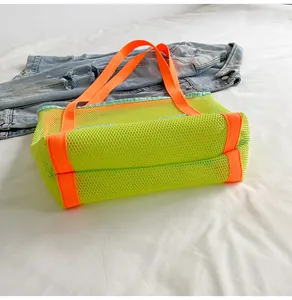 Detail of neon green mesh beach tote bag with vibrant orange handles and base reinforcement