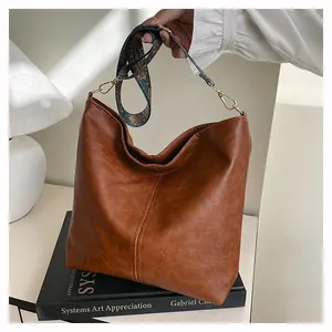 Detail of vintage brown tote bag featuring a colorful ethnic style wide shoulder strap