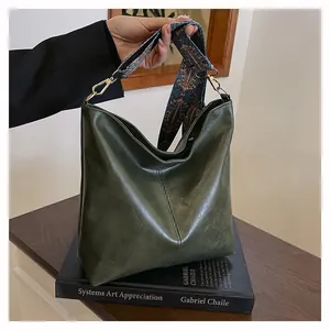 Detail of green leather hobo bag with ethnic style printed strap and gold buckle