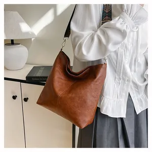 Detail of vintage brown tote bag featuring a bohemian woven strap and gold metal buckles