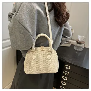 Detalle del bolso de paja crema con tejido de espiga y cremalleras metálicas doradas