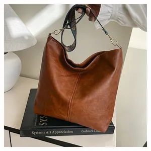 Close-up of vintage brown leather tote bag with a floral patterned detachable strap