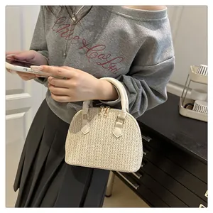 Detalle del bolso tejido en forma de concha con textura y asa de cuero blanco