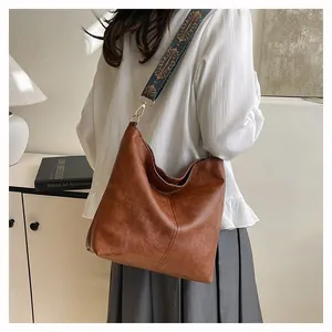 Brown vintage leather tote bag featuring a wide colorful ethnic embroidery shoulder strap