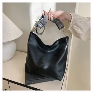 Detail of black hobo bag with textured finish and bohemian floral woven strap