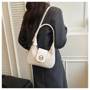 Detail of cream woven shoulder bag with gold M logo buckle and adjustable leather strap