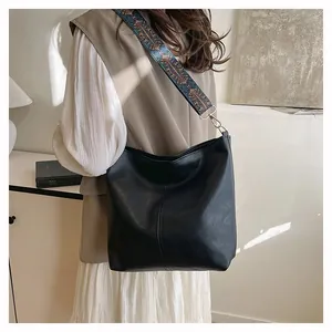 Detail of black matte tote bag with bohemian embroidered wide strap on female model